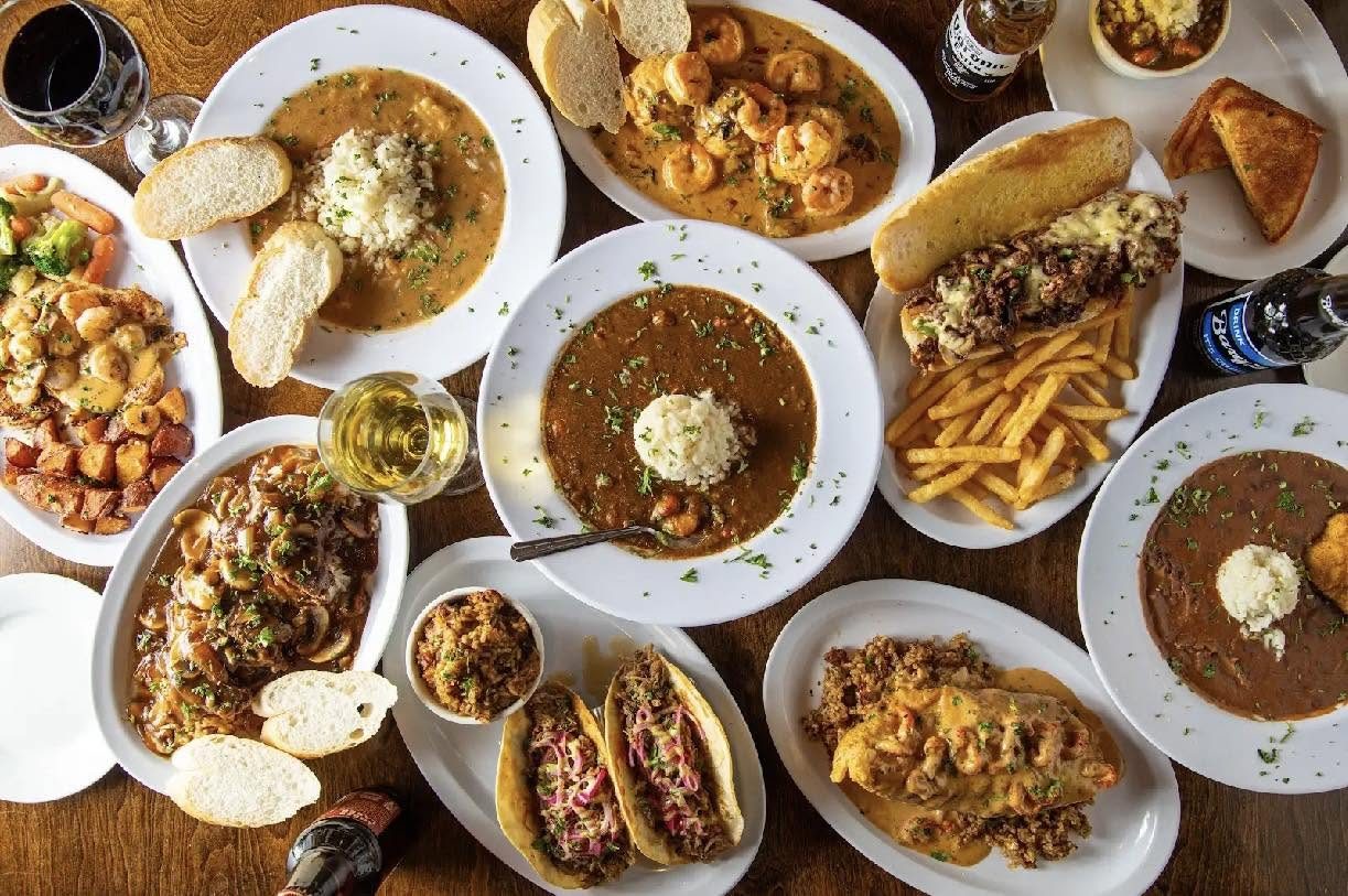 A table of New Orleans food — gumbo, étouffée, plates, bread